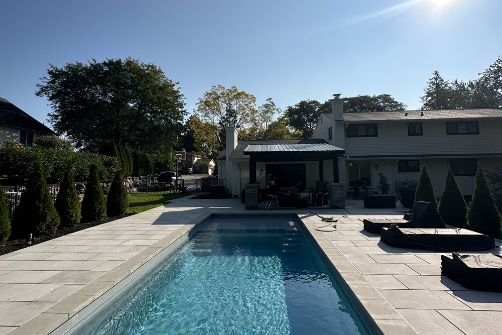 Backyard pool with covered pergola and stone patio